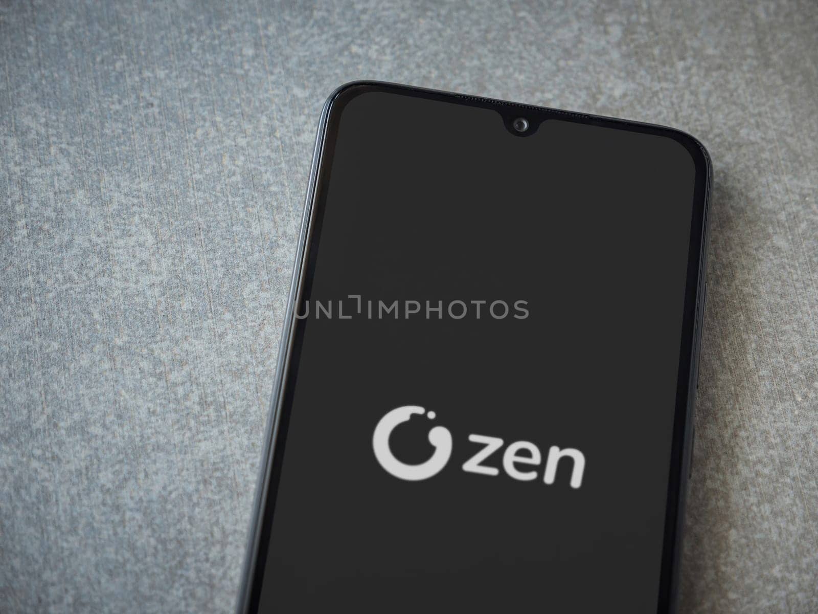 Lod, Israel - July 16,2023: ZEN.COM app launch screen on smartphone on ceramic stone background. Top view flat lay with copy space.