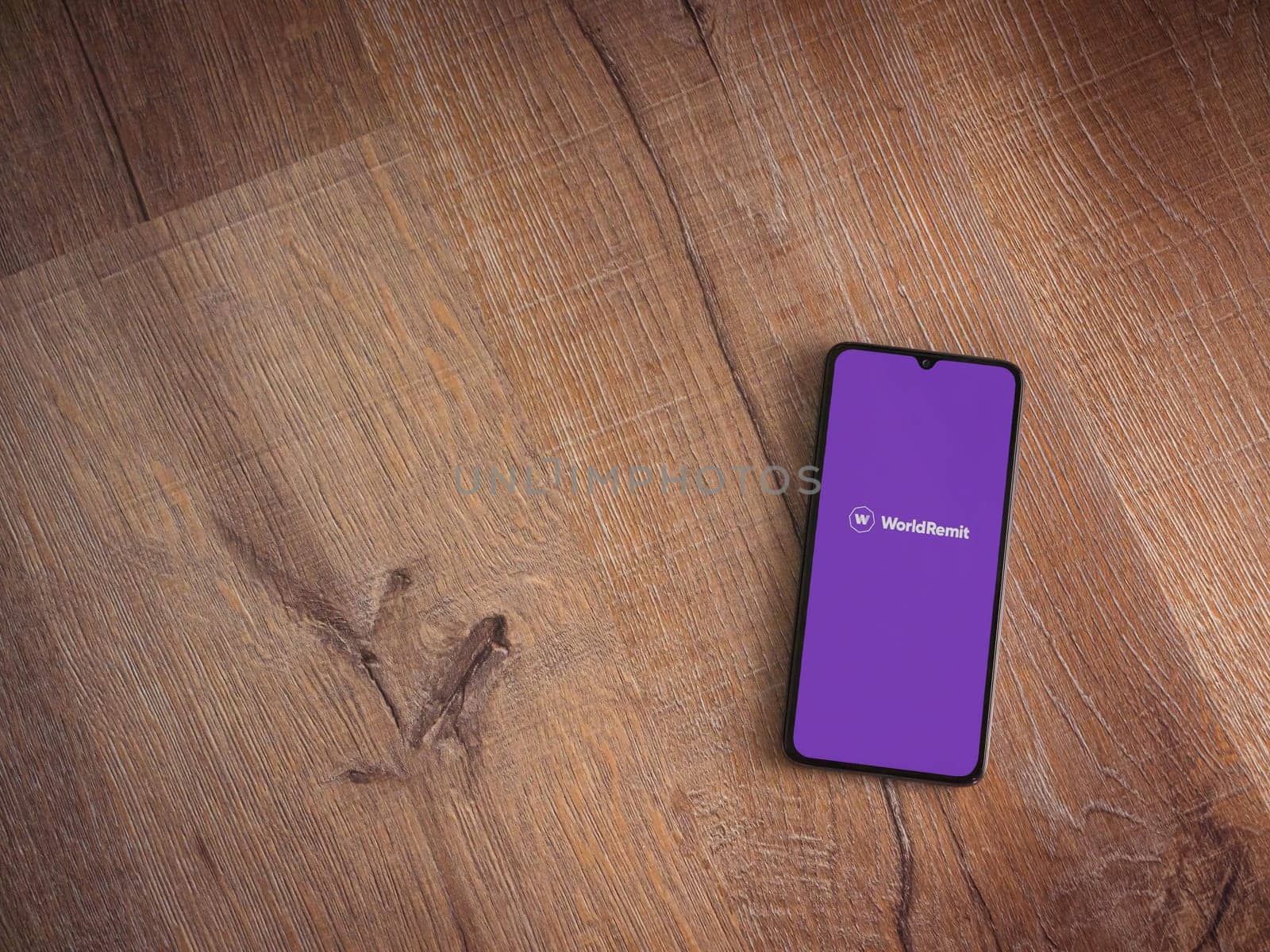 Lod, Israel - July 16,2023: WorldRemit app launch screen on smartphone on wooden background. Top view flat lay with copy space.