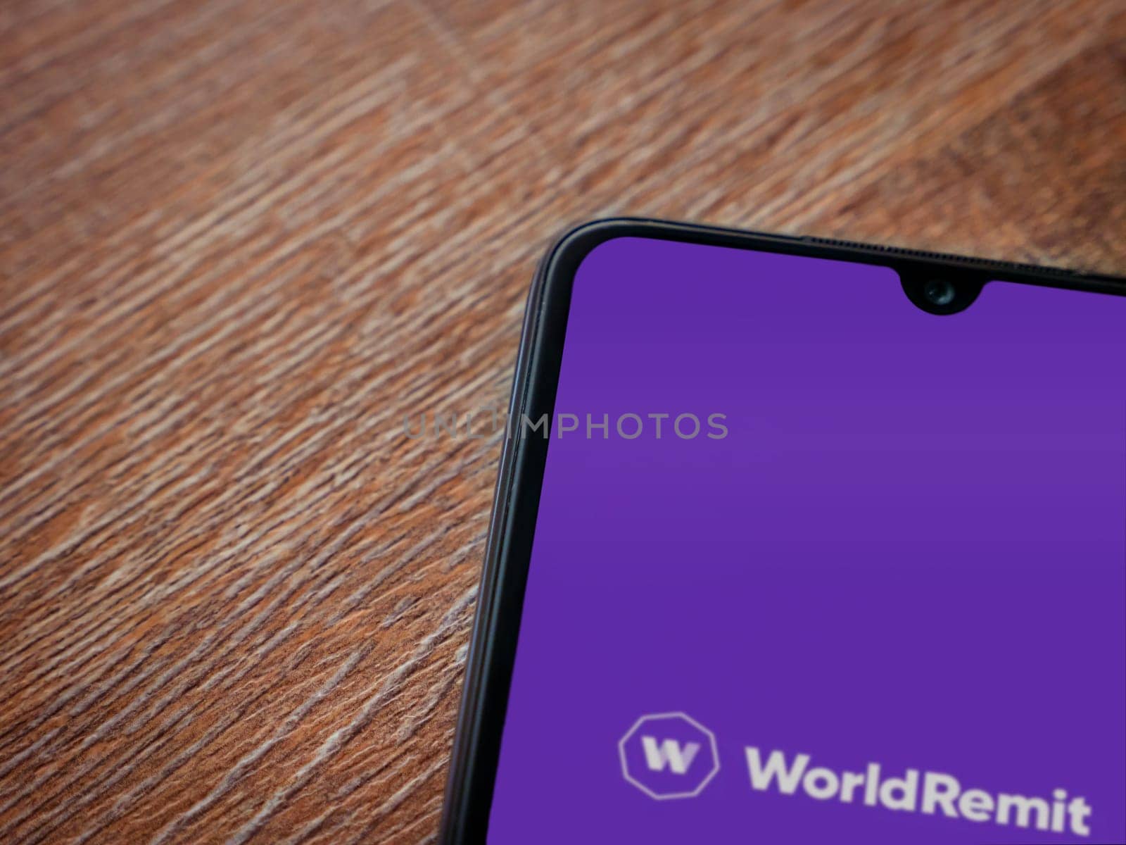 Lod, Israel - July 16,2023: WorldRemit app launch screen on smartphone on wooden background. Top view flat lay with copy space.