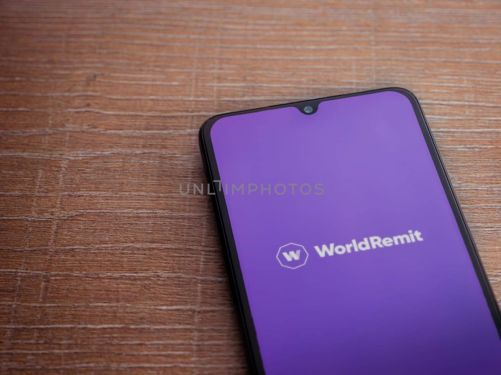 Lod, Israel - July 16,2023: WorldRemit app launch screen on smartphone on wooden background. Top view flat lay with copy space.