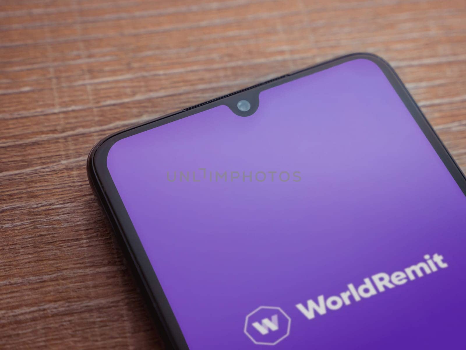 Lod, Israel - July 16,2023: WorldRemit app launch screen on smartphone on wooden background. Top view flat lay with copy space.