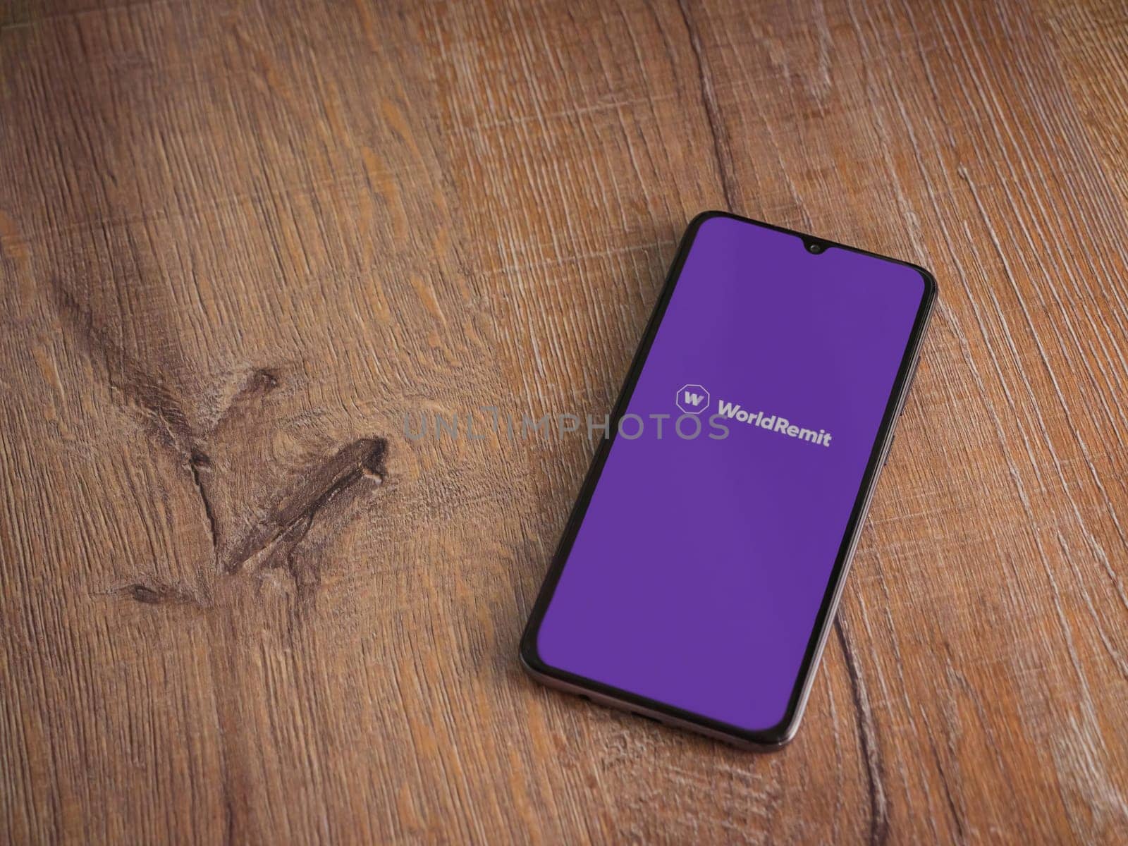 Lod, Israel - July 16,2023: WorldRemit app launch screen on smartphone on wooden background. Top view flat lay with copy space.