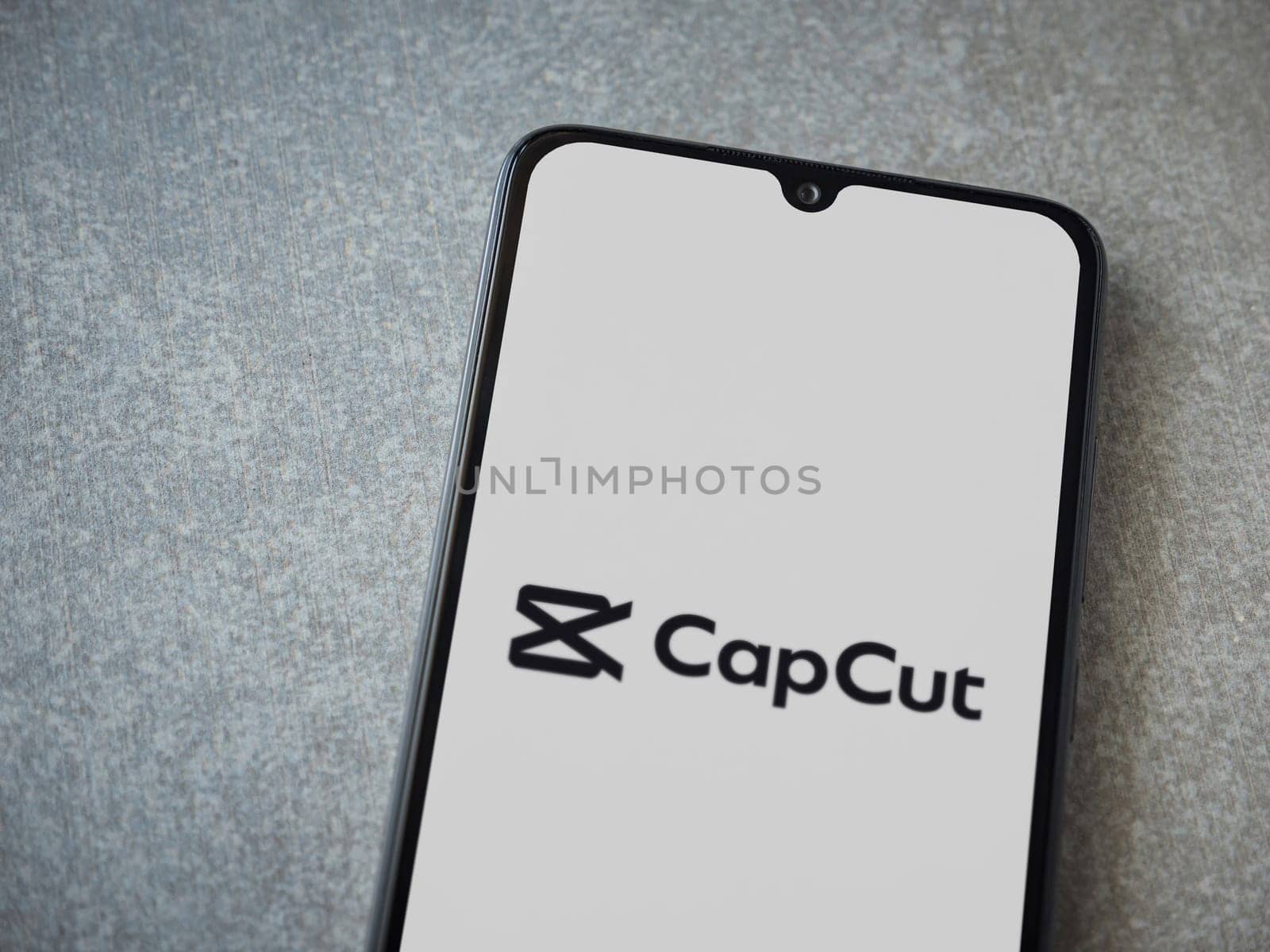 Lod, Israel - July 16,2023: CapCut app launch screen on smartphone on ceramic stone background.. Top view flat lay with copy space.