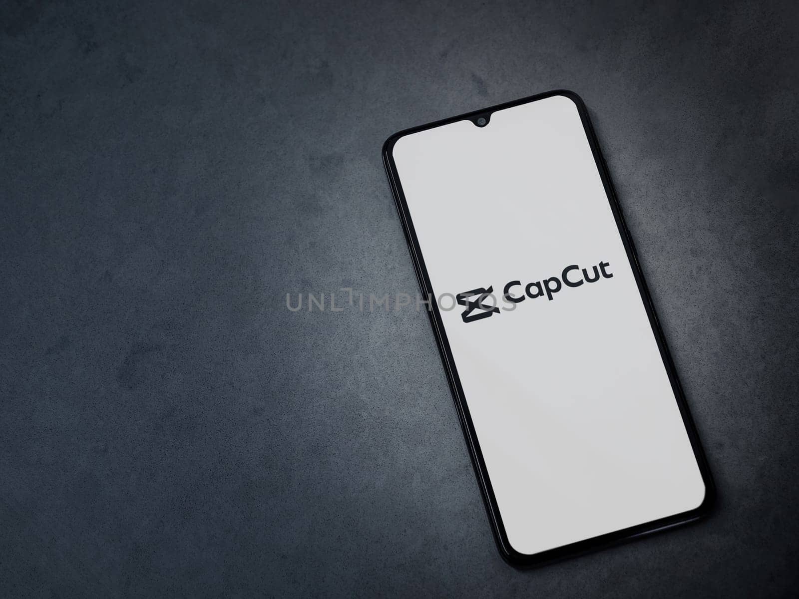 Lod, Israel - July 16,2023: CapCut app launch screen on smartphone on dark marble stone background. Top view flat lay with copy space.