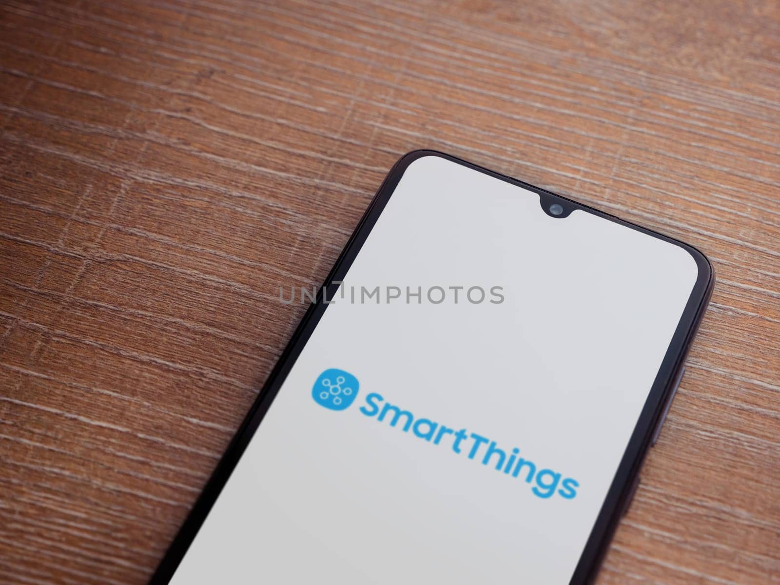 Lod, Israel - July 16,2023: Smartthings app launch screen on smartphone on wooden background. Top view flat lay with copy space.