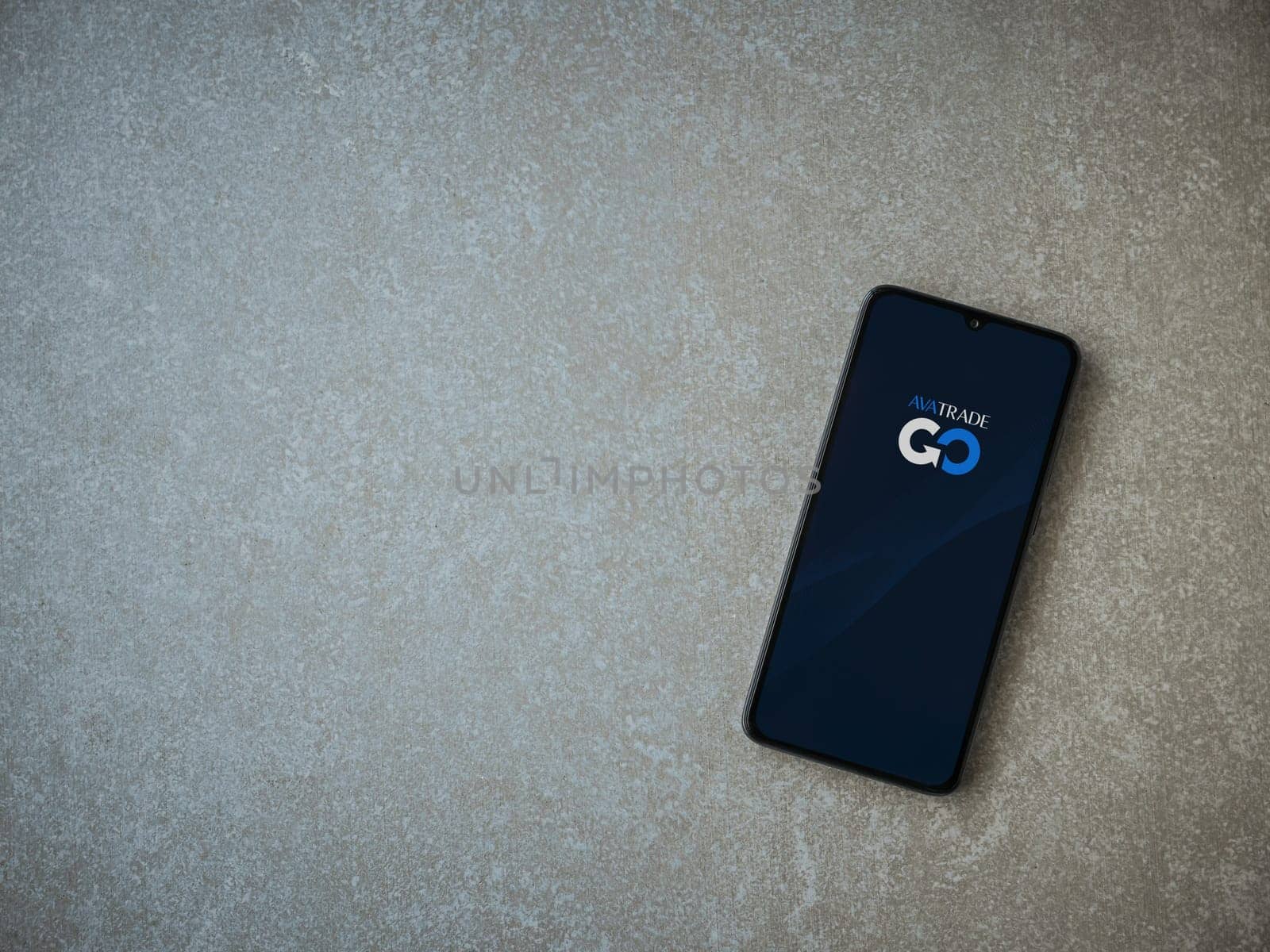 Lod, Israel - July 16,2023: Avatrade app launch screen on smartphone on ceramic stone background. Top view flat lay with copy space.