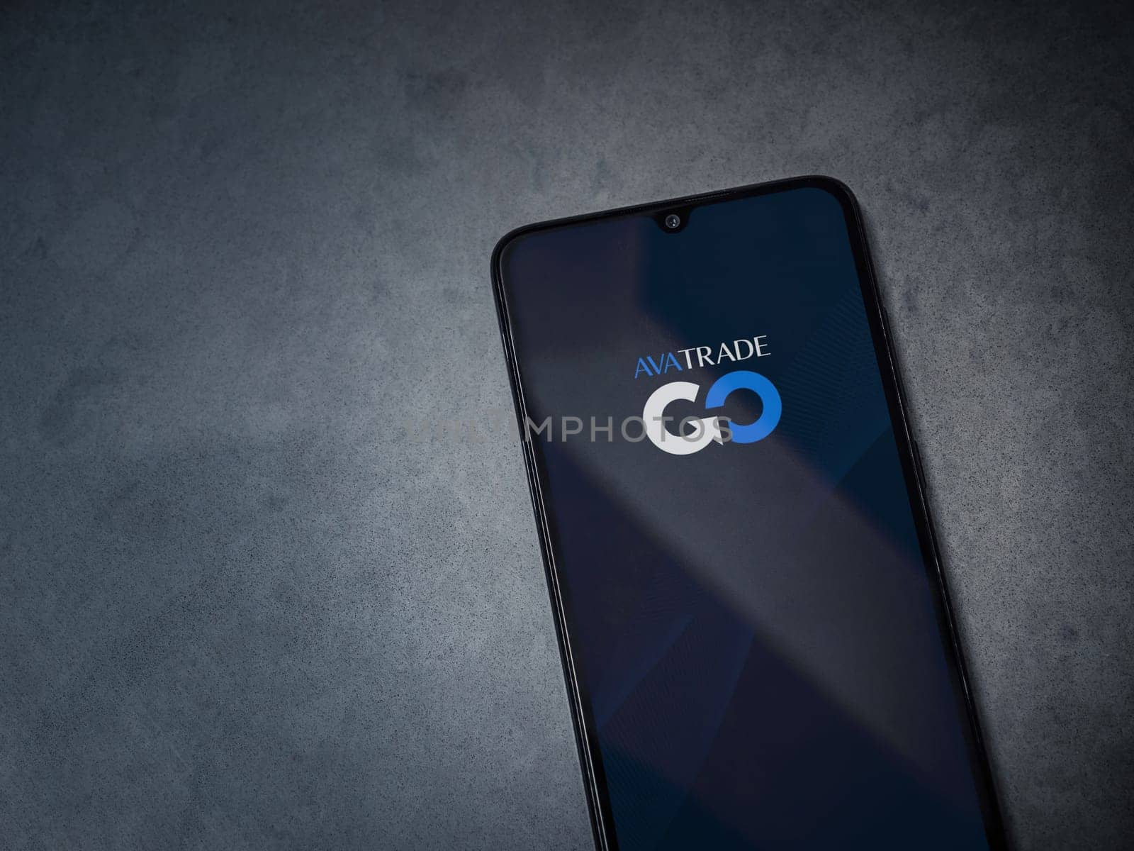 Lod, Israel - July 16,2023: Avatrade app launch screen on smartphone on dark marble stone background. Top view flat lay with copy space.