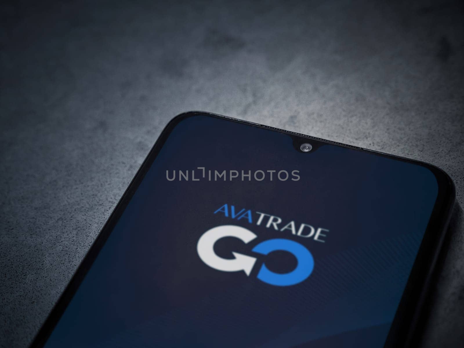Lod, Israel - July 16,2023: Avatrade app launch screen on smartphone on dark marble stone background. Top view flat lay with copy space.