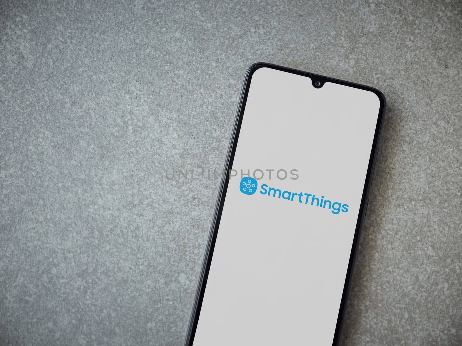 Lod, Israel - July 16,2023: Smartthings app launch screen on smartphone on ceramic stone background. Top view flat lay with copy space.