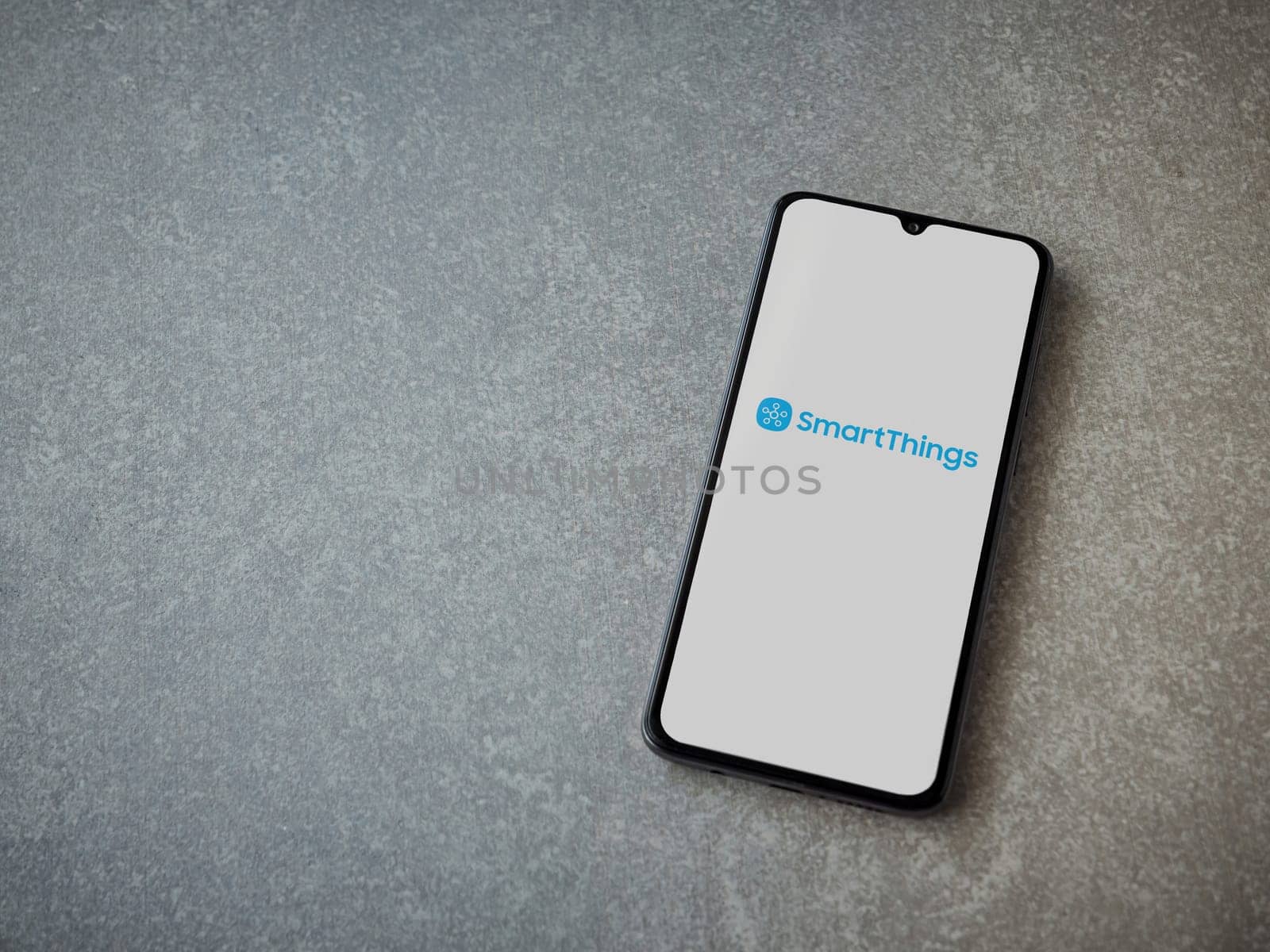 Lod, Israel - July 16,2023: Smartthings app launch screen on smartphone on ceramic stone background. Top view flat lay with copy space.