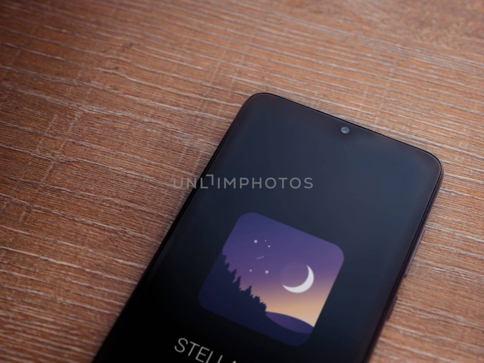 Lod, Israel - July 16,2023: Stellarium - Star Map app launch screen on smartphone on wooden background. Top view flat lay with copy space.