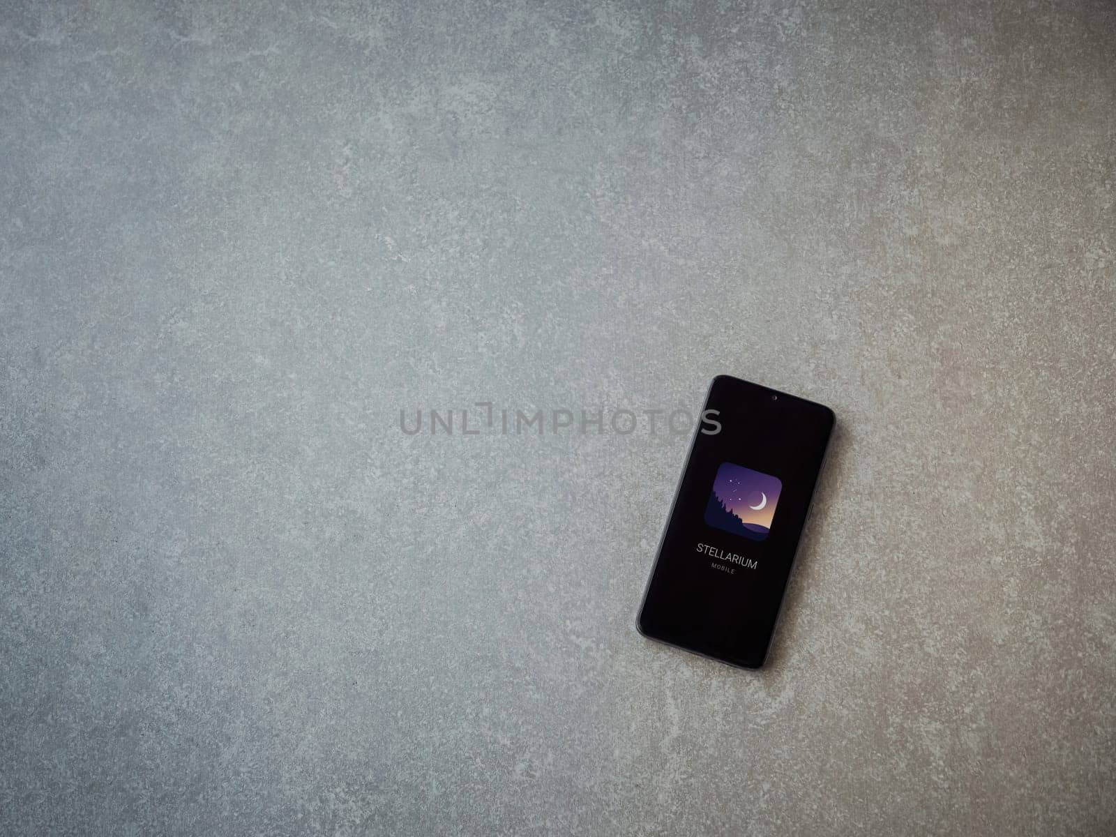 Lod, Israel - July 16,2023: Stellarium - Star Map app launch screen on smartphone on ceramic stone background. Top view flat lay with copy space.