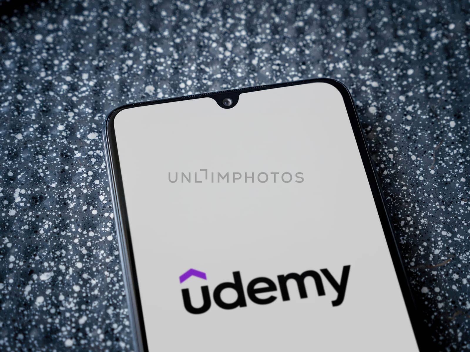 Lod, Israel - July 16,2023: Udemy app launch screen on the display of a black mobile smartphone on a metallic background. Close up top view flat lay.