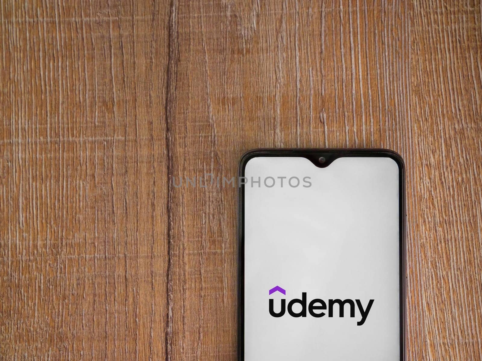 Lod, Israel - July 16,2023: Udemy app launch screen on smartphone on wooden background. Top view flat lay with copy space.