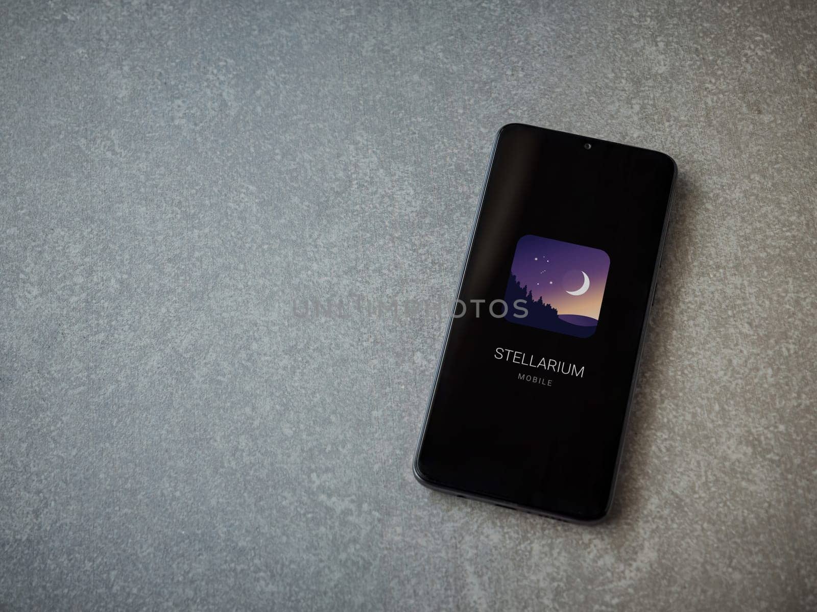 Lod, Israel - July 16,2023: Stellarium - Star Map app launch screen on smartphone on ceramic stone background. Top view flat lay with copy space.