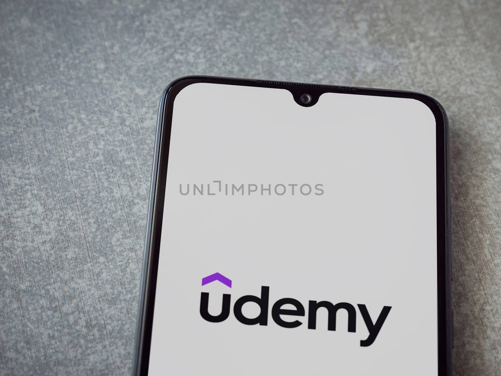 Lod, Israel - July 16,2023: Udemy app launch screen on smartphone on ceramic stone background. Top view flat lay with copy space.
