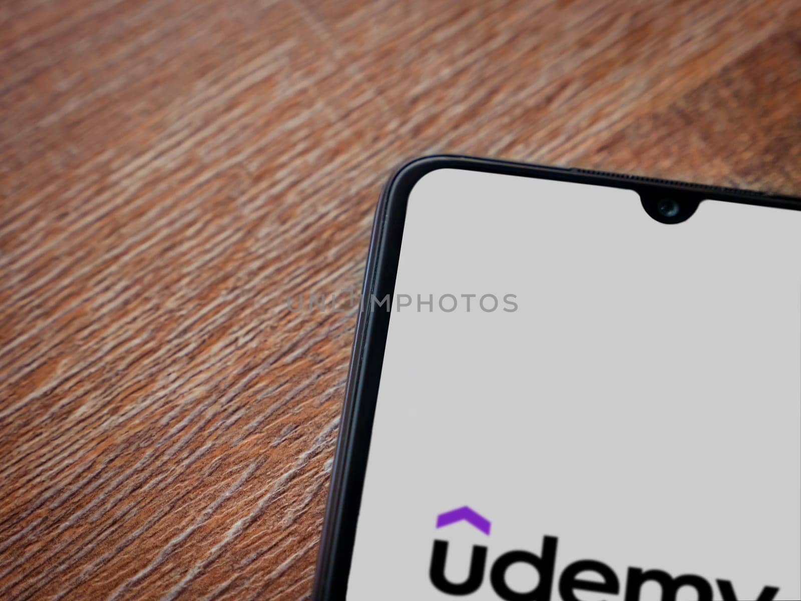 Lod, Israel - July 16,2023: Udemy app launch screen on smartphone on wooden background. Top view flat lay with copy space.