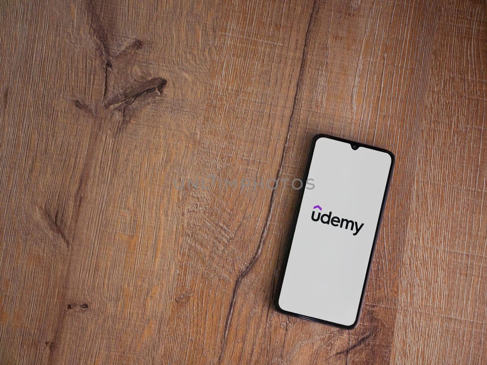 Lod, Israel - July 16,2023: Udemy app launch screen on smartphone on wooden background. Top view flat lay with copy space.