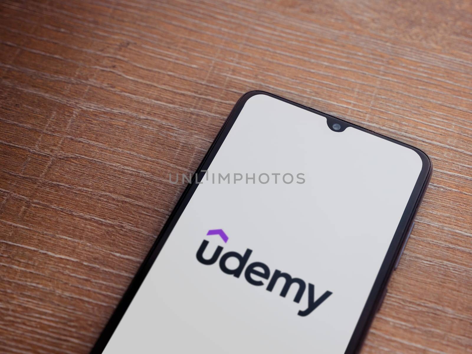 Lod, Israel - July 16,2023: Udemy app launch screen on smartphone on wooden background. Top view flat lay with copy space.