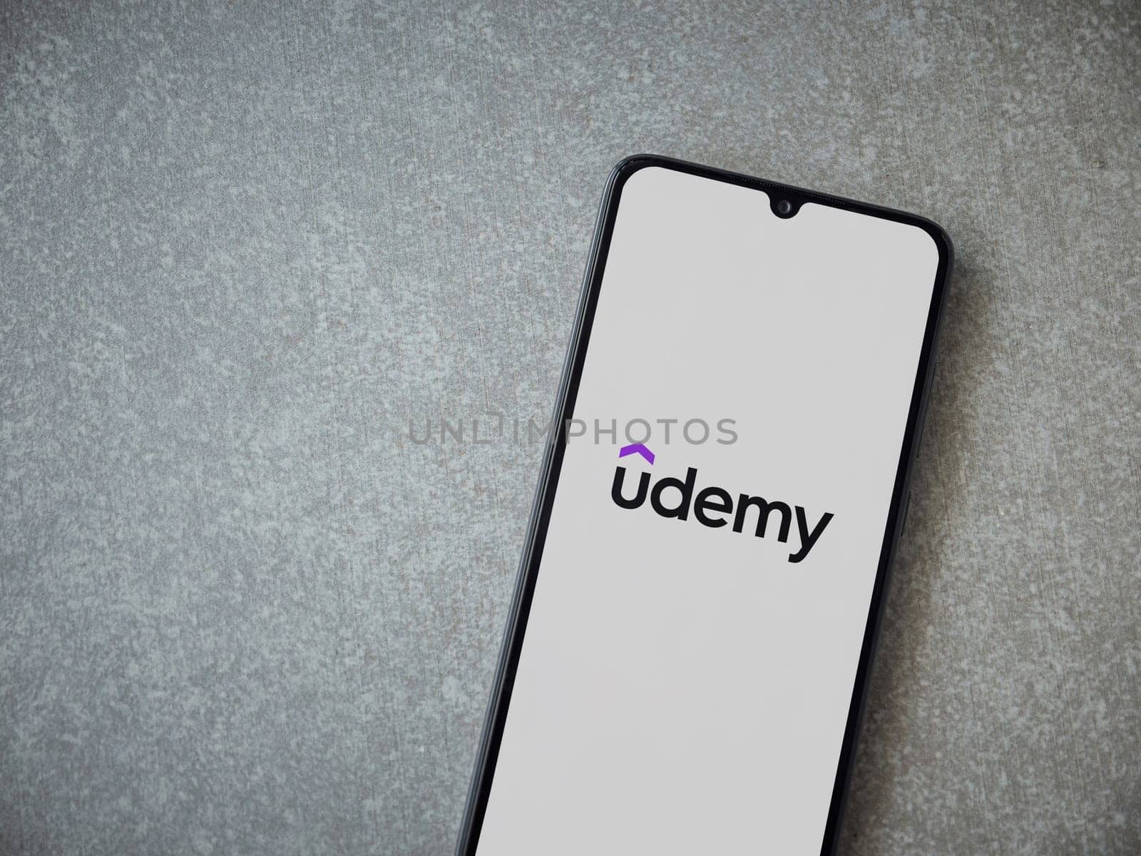 Lod, Israel - July 16,2023: Udemy app launch screen on smartphone on ceramic stone background. Top view flat lay with copy space.
