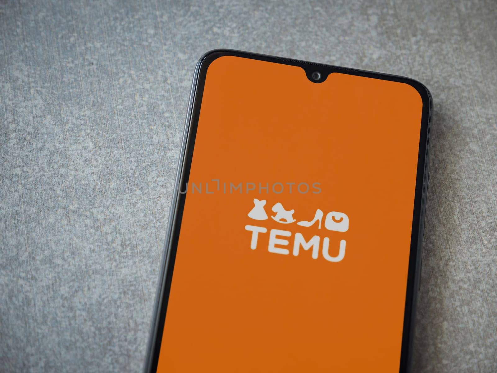 Lod, Israel - July 16,2023: Temu app launch screen on smartphone on ceramic stone background. Top view flat lay with copy space.