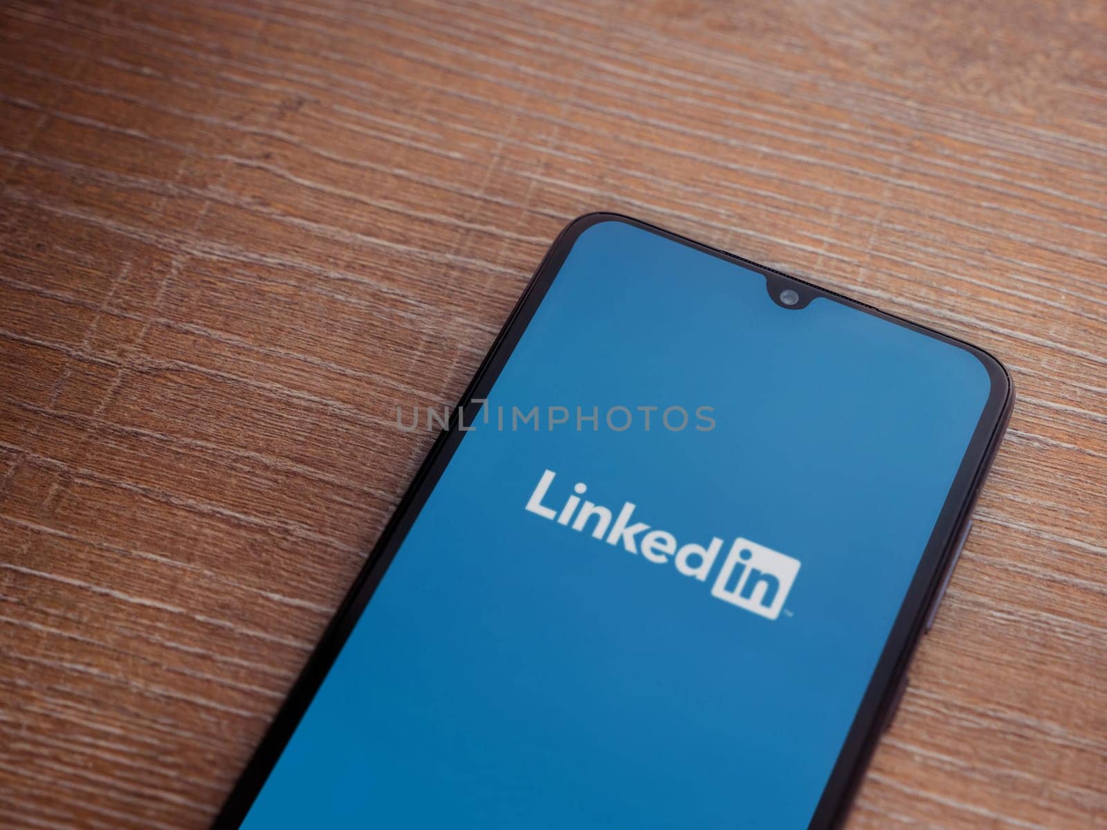 Lod, Israel - July 16,2023: LinkedIn app launch screen on smartphone on wooden background. Top view flat lay with copy space.