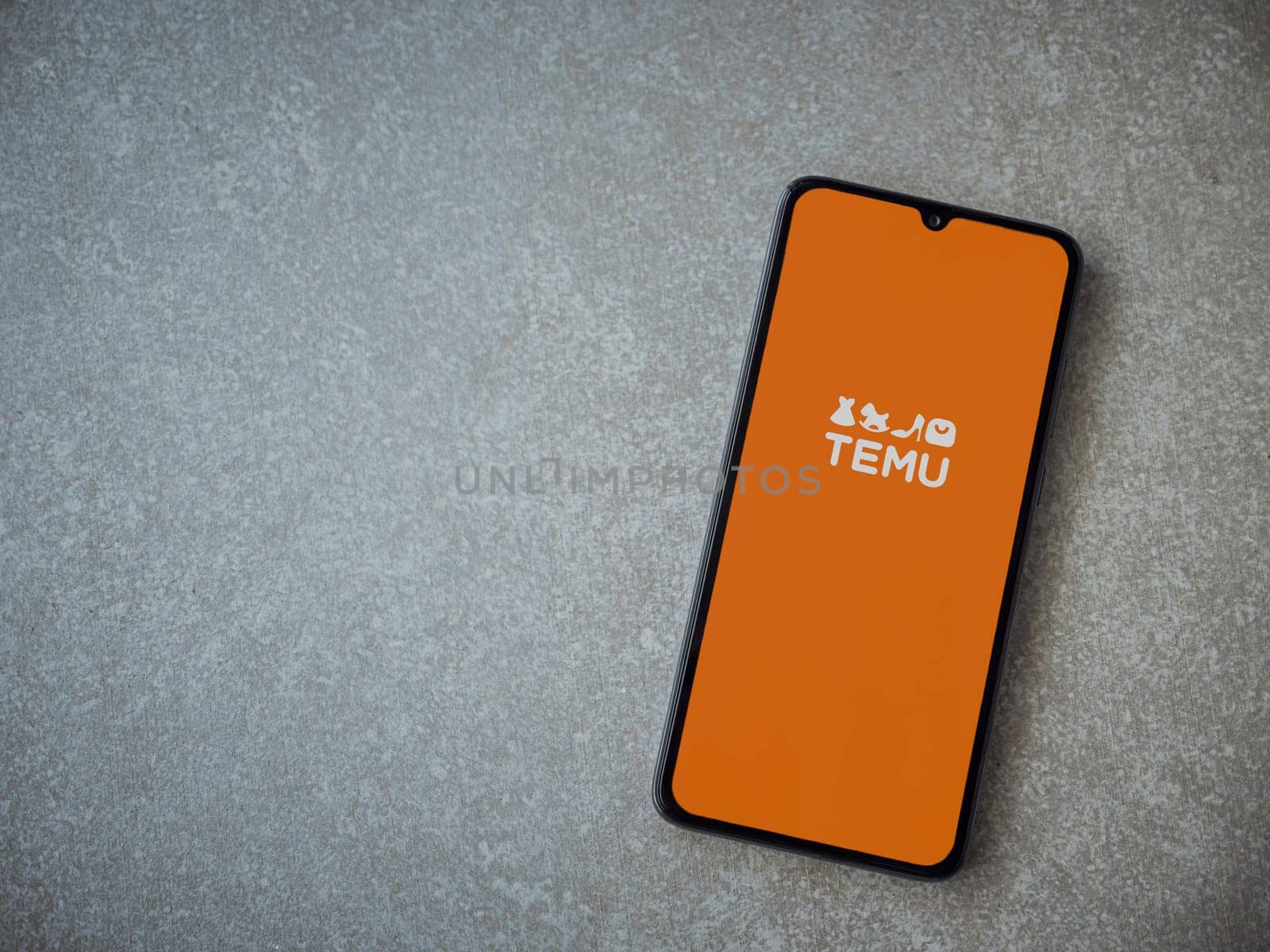 Lod, Israel - July 16,2023: Temu app launch screen on smartphone on ceramic stone background. Top view flat lay with copy space.