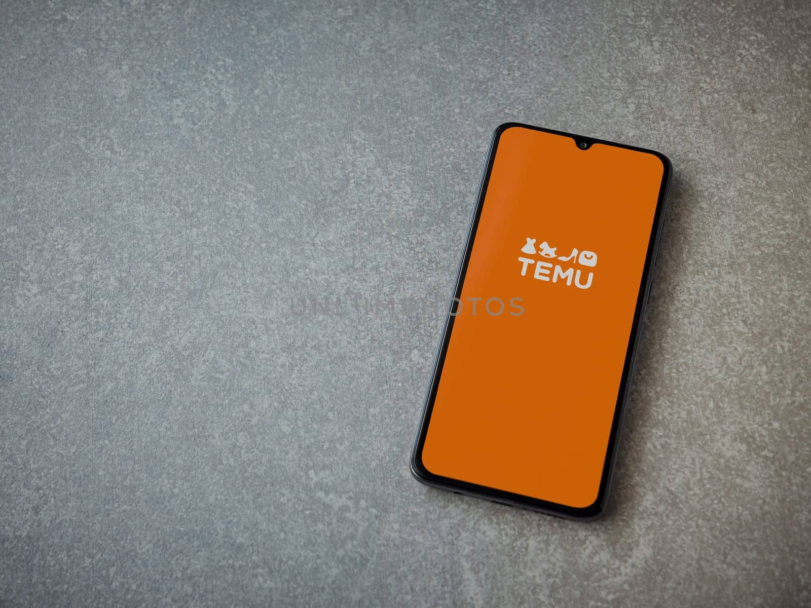 Lod, Israel - July 16,2023: Temu app launch screen on smartphone on ceramic stone background. Top view flat lay with copy space.