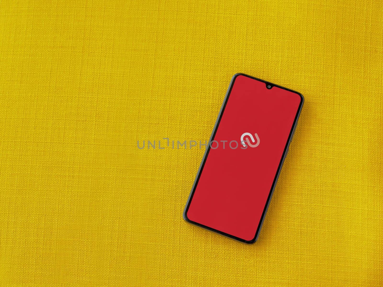 Lod, Israel - July 16,2023: Twilio Authy Authenticator app launch screen on smartphone on yellow fabric background. Top view flat lay with copy space.