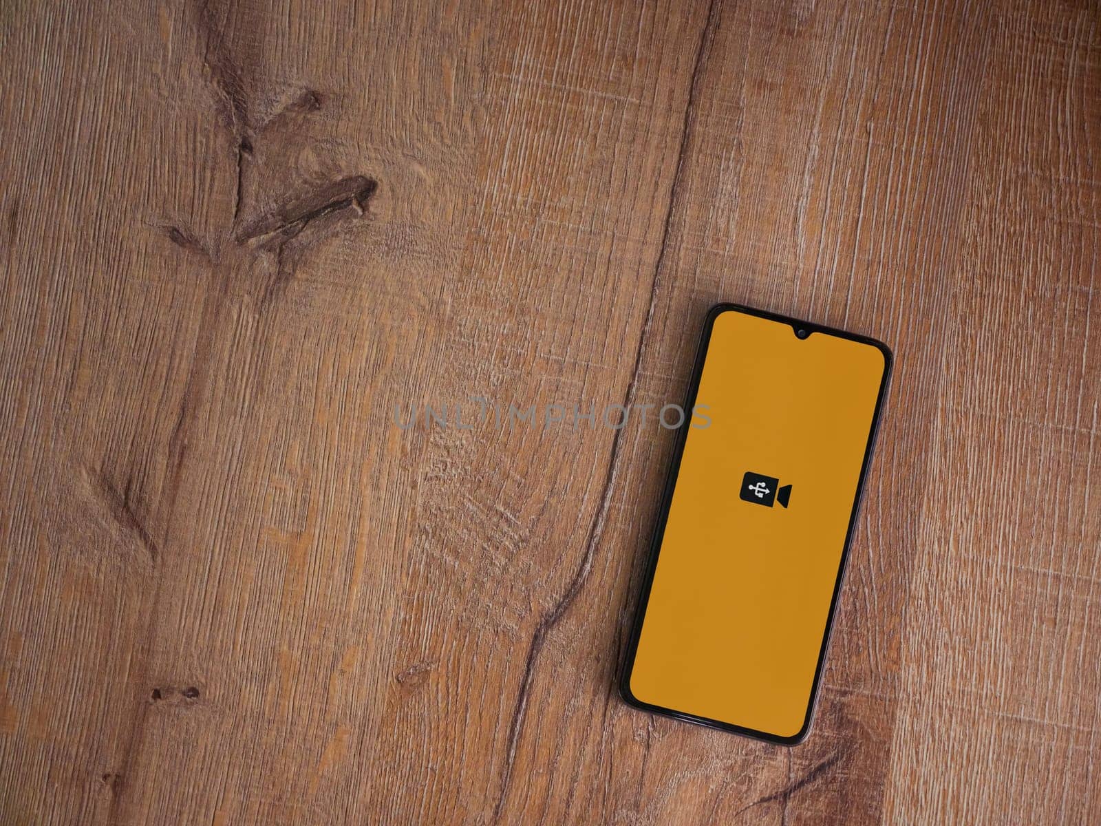 Lod, Israel - July 16,2023: USB Camera app launch screen on smartphone on wooden background. Top view flat lay with copy space.