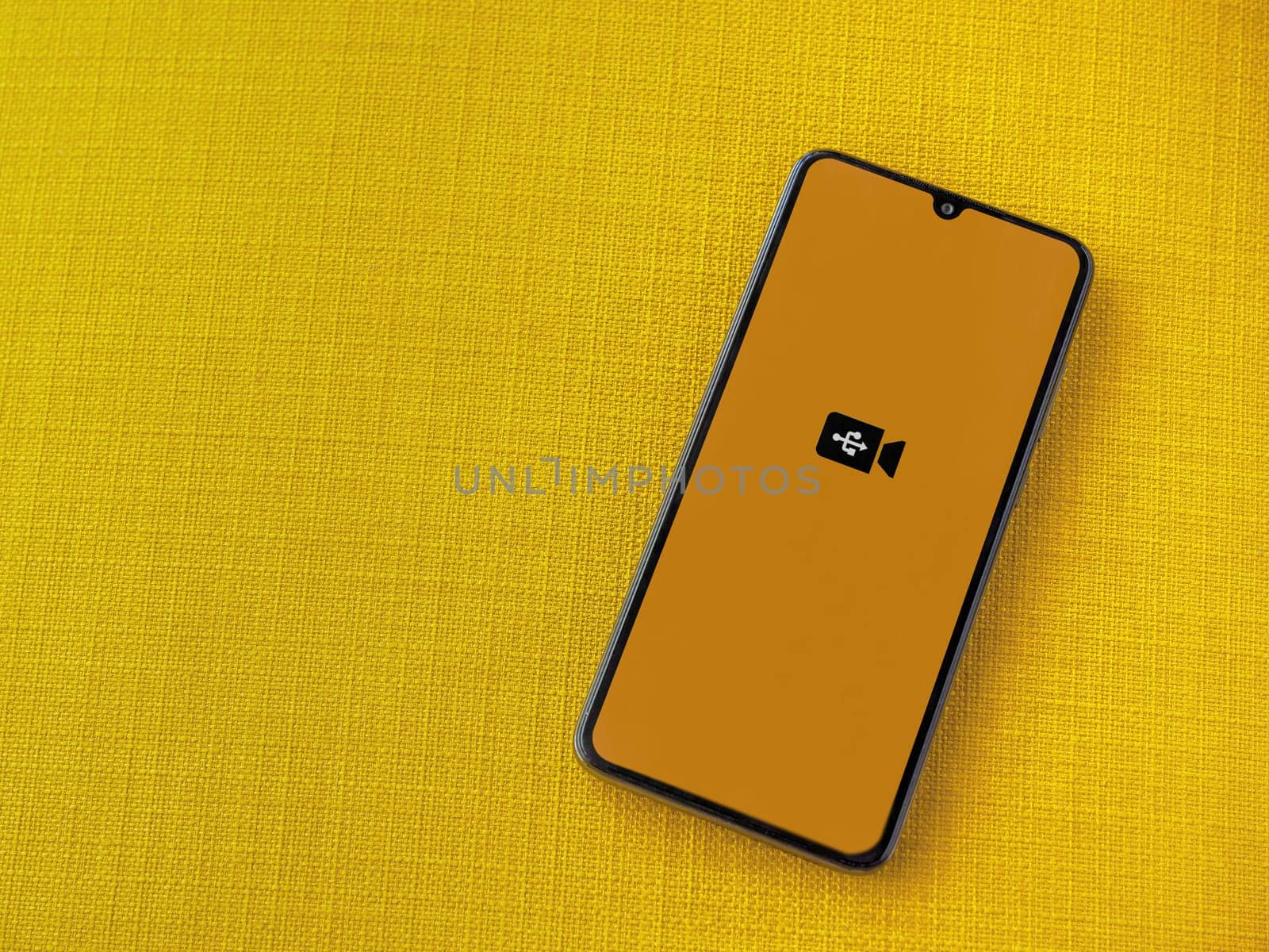 Lod, Israel - July 16,2023: USB Camera app launch screen on smartphone on yellow fabric background. Top view flat lay with copy space.
