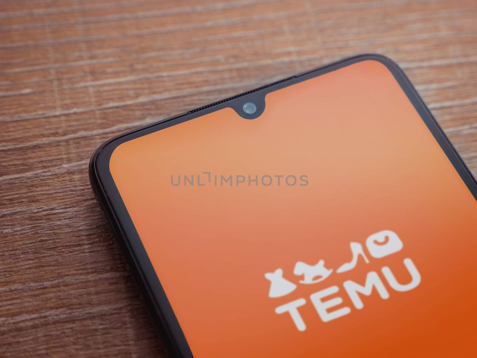 Lod, Israel - July 16,2023: Temu app launch screen on smartphone on wooden background. Top view flat lay with copy space.