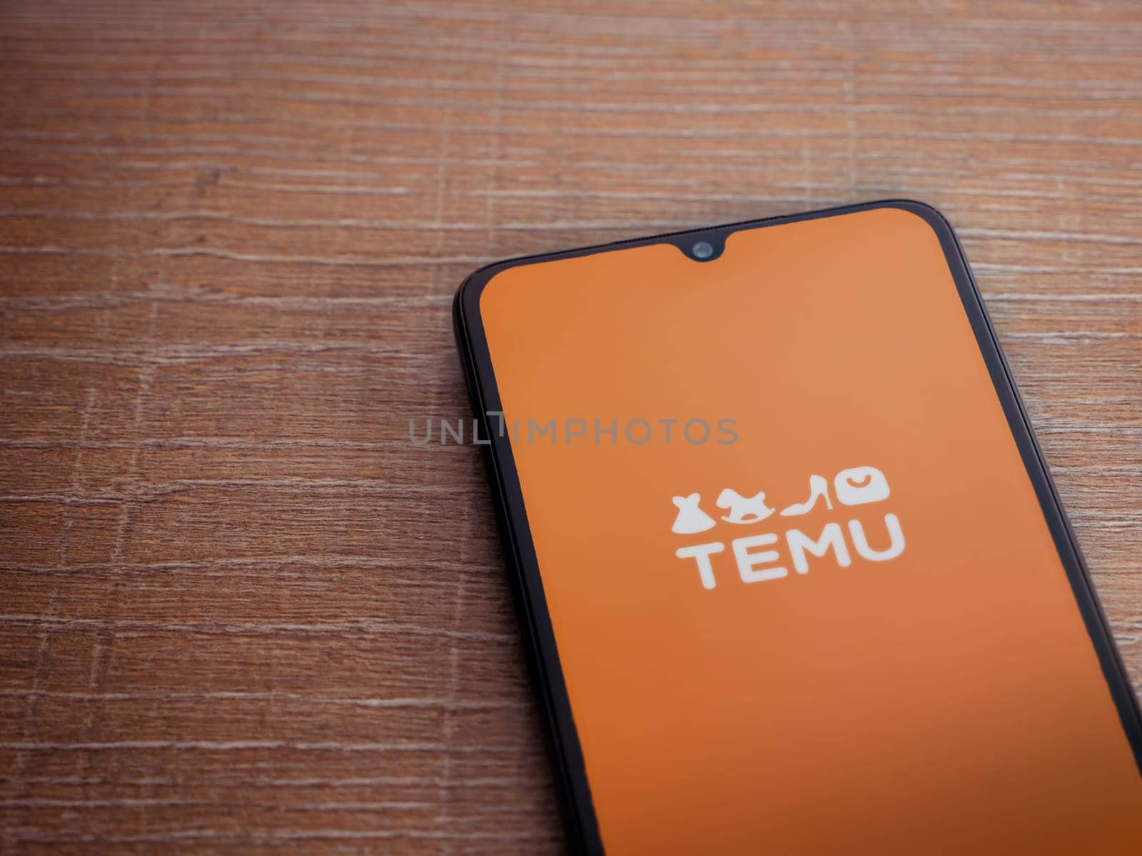 Lod, Israel - July 16,2023: Temu app launch screen on smartphone on wooden background. Top view flat lay with copy space.
