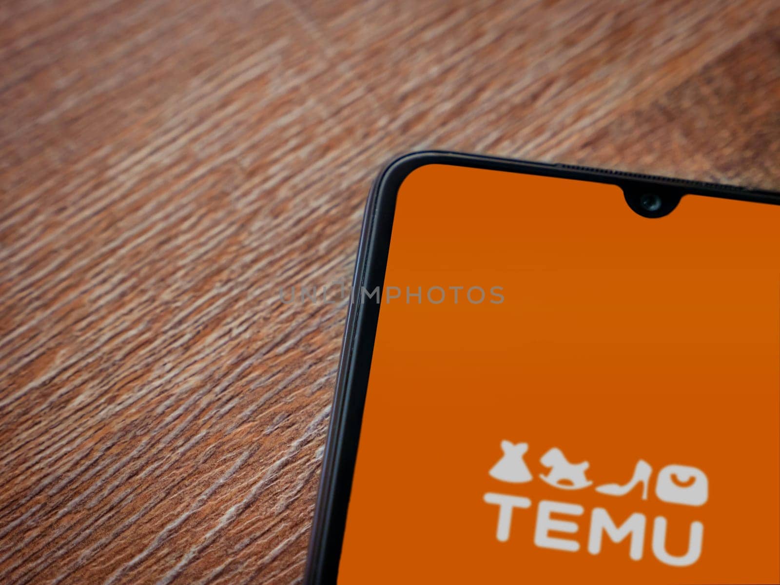 Lod, Israel - July 16,2023: Temu app launch screen on smartphone on wooden background. Top view flat lay with copy space.