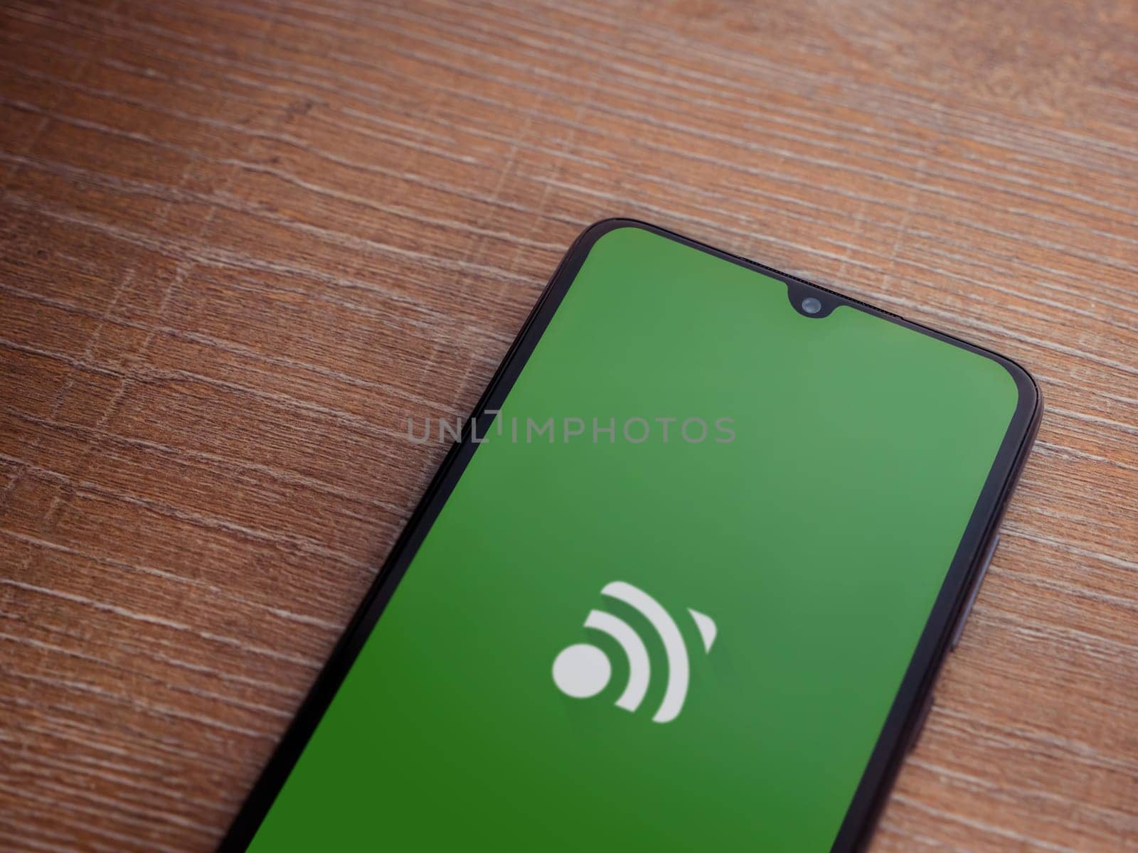 Lod, Israel - July 16,2023: Unified Remote app launch screen on smartphone on wooden background. Top view flat lay with copy space.