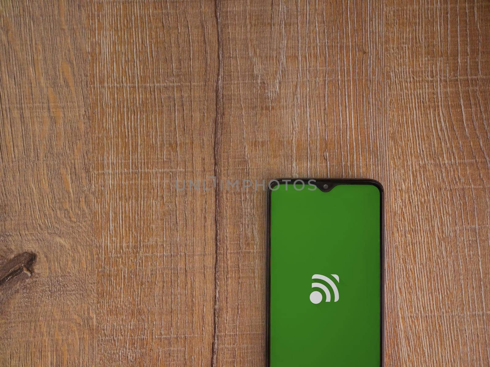 Lod, Israel - July 16,2023: Unified Remote app launch screen on smartphone on wooden background. Top view flat lay with copy space.