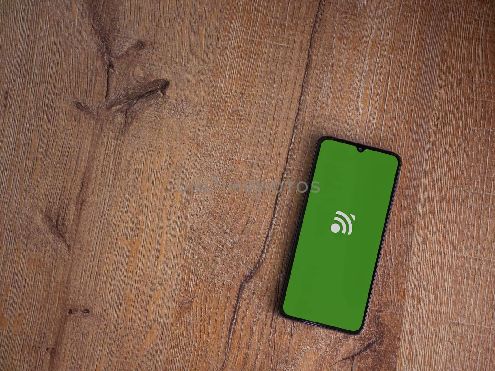 Lod, Israel - July 16,2023: Unified Remote app launch screen on smartphone on wooden background. Top view flat lay with copy space.
