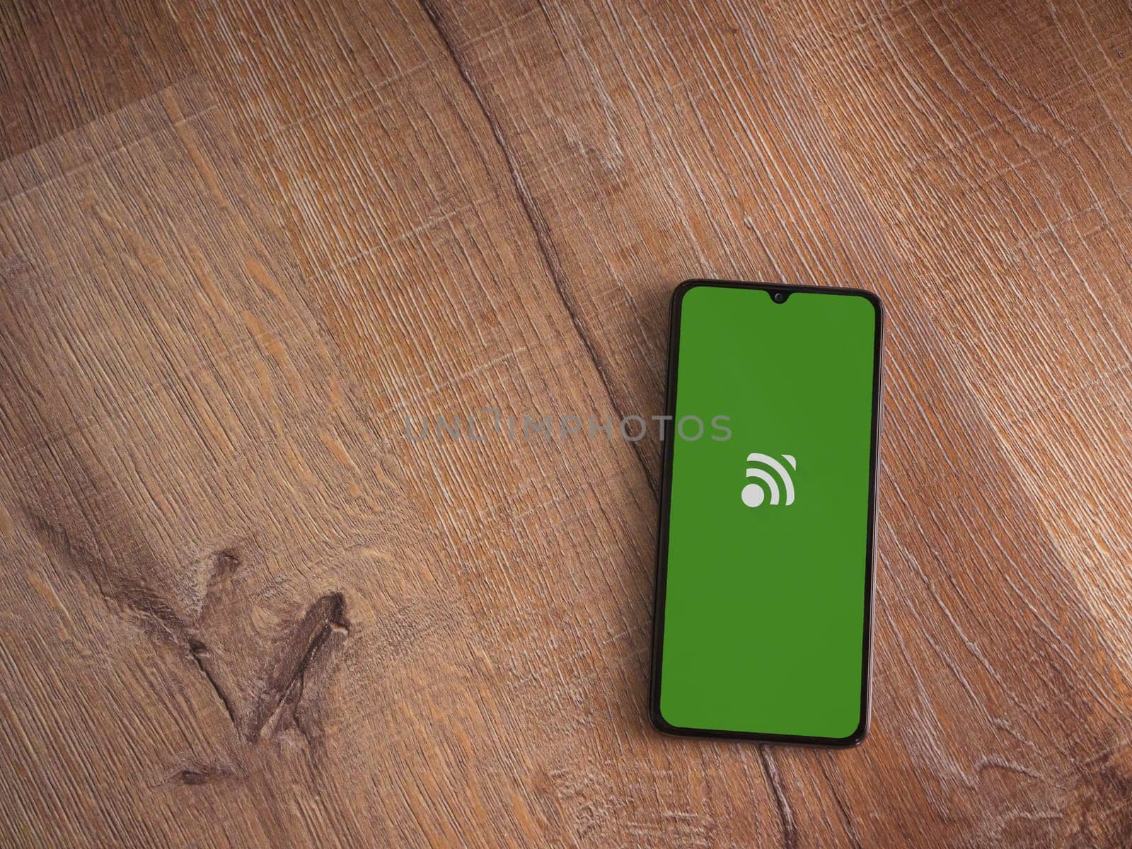Lod, Israel - July 16,2023: Unified Remote app launch screen on smartphone on wooden background. Top view flat lay with copy space.