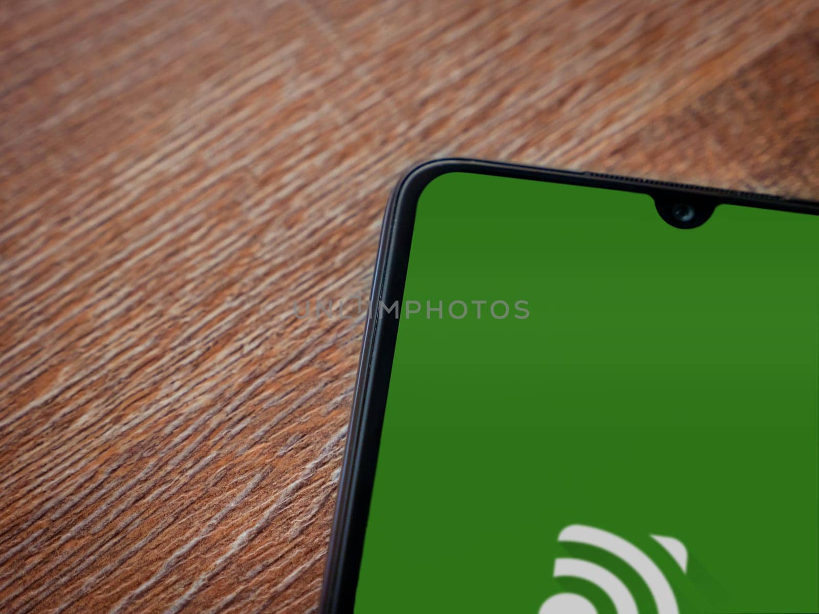 Lod, Israel - July 16,2023: Unified Remote app launch screen on smartphone on wooden background. Top view flat lay with copy space.