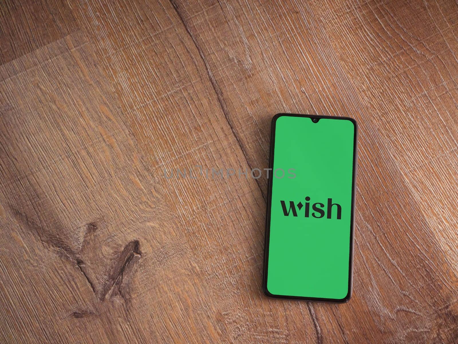 Lod, Israel - July 16,2023: Wish app launch screen on smartphone on wooden background. Top view flat lay with copy space.