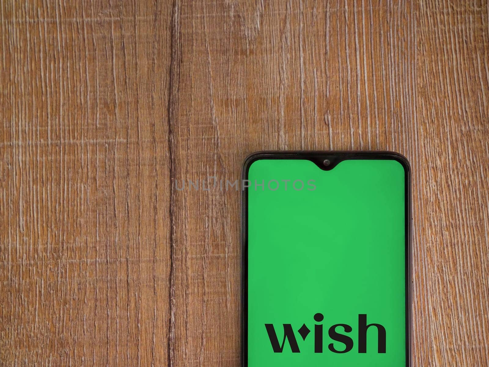 Lod, Israel - July 16,2023: Wish app launch screen on smartphone on wooden background. Top view flat lay with copy space.