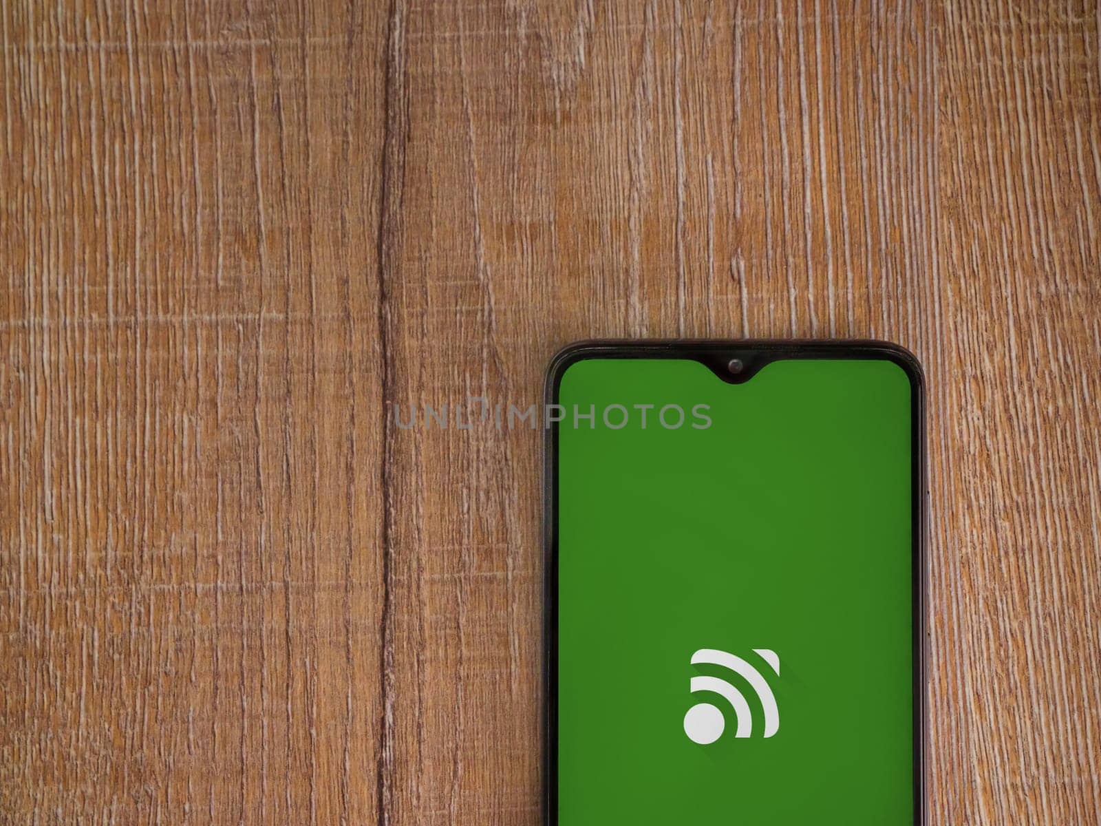 Lod, Israel - July 16,2023: Unified Remote app launch screen on smartphone on wooden background. Top view flat lay with copy space.