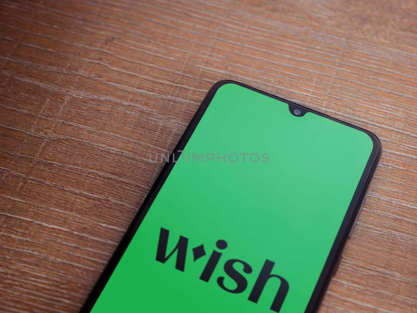 Lod, Israel - July 16,2023: Wish app launch screen on smartphone on wooden background. Top view flat lay with copy space.