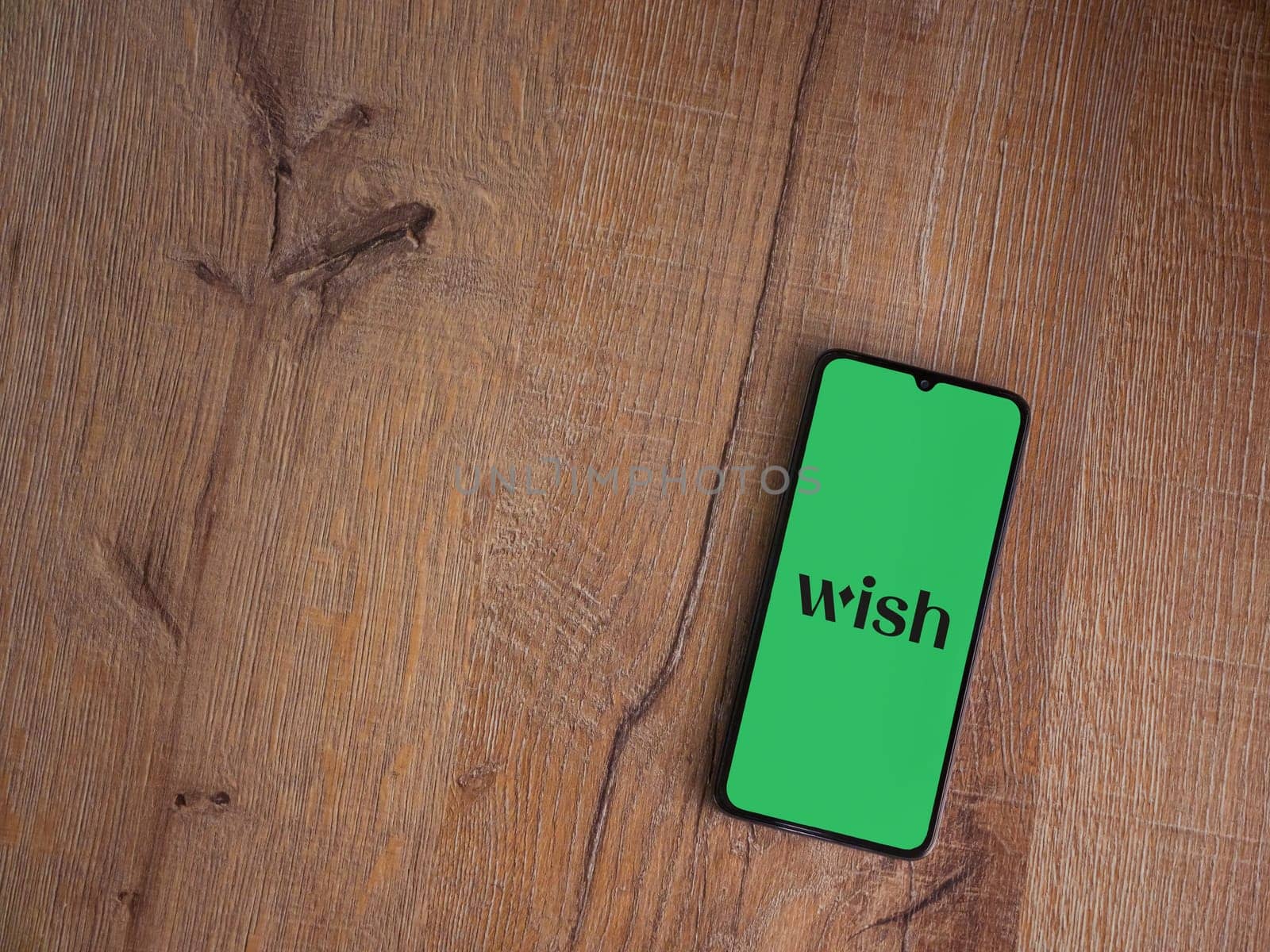 Lod, Israel - July 16,2023: Wish app launch screen on smartphone on wooden background. Top view flat lay with copy space.