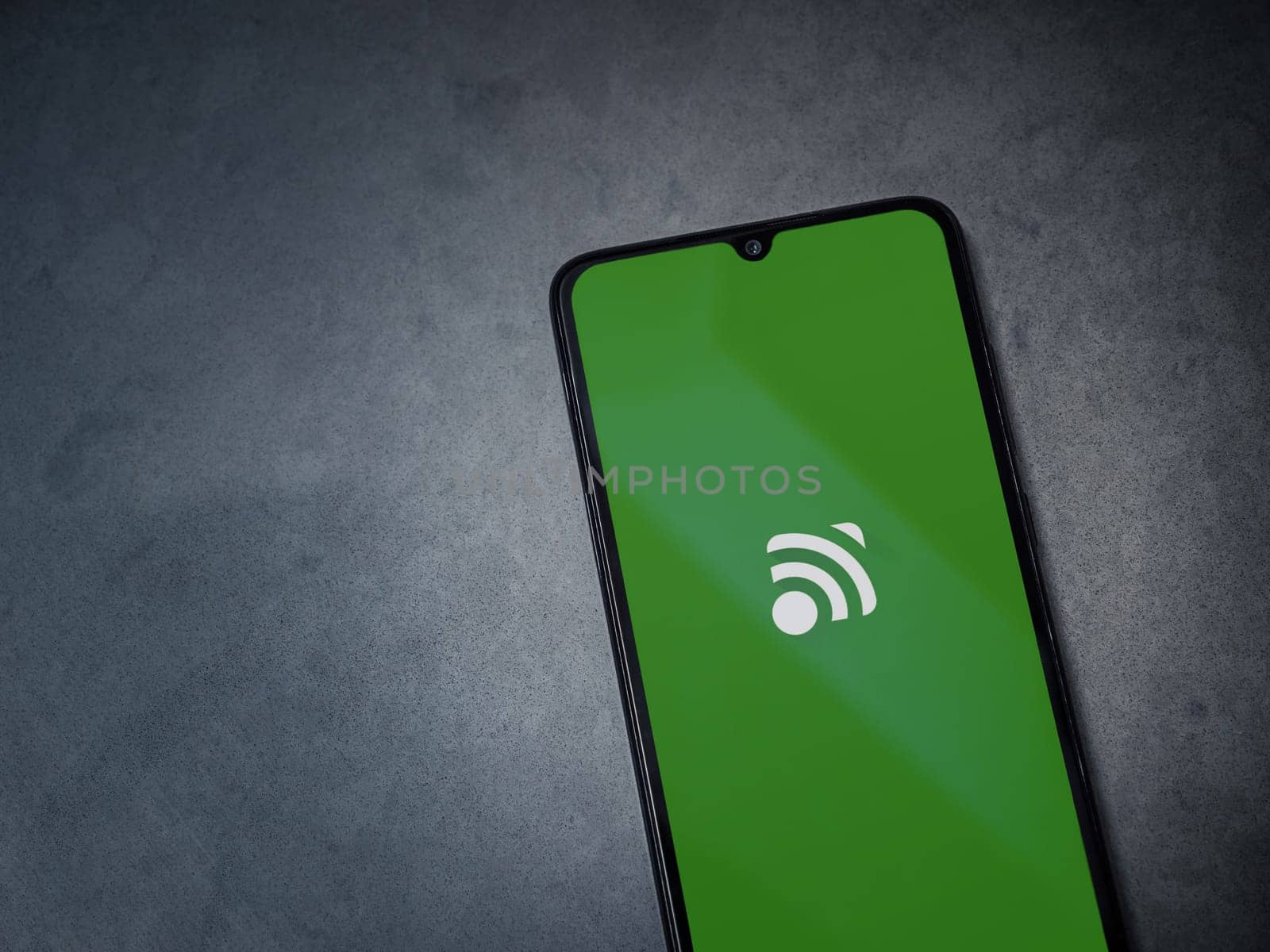 Lod, Israel - July 16,2023: Unified Remote app launch screen on smartphone on dark marble stone background. Top view flat lay with copy space.