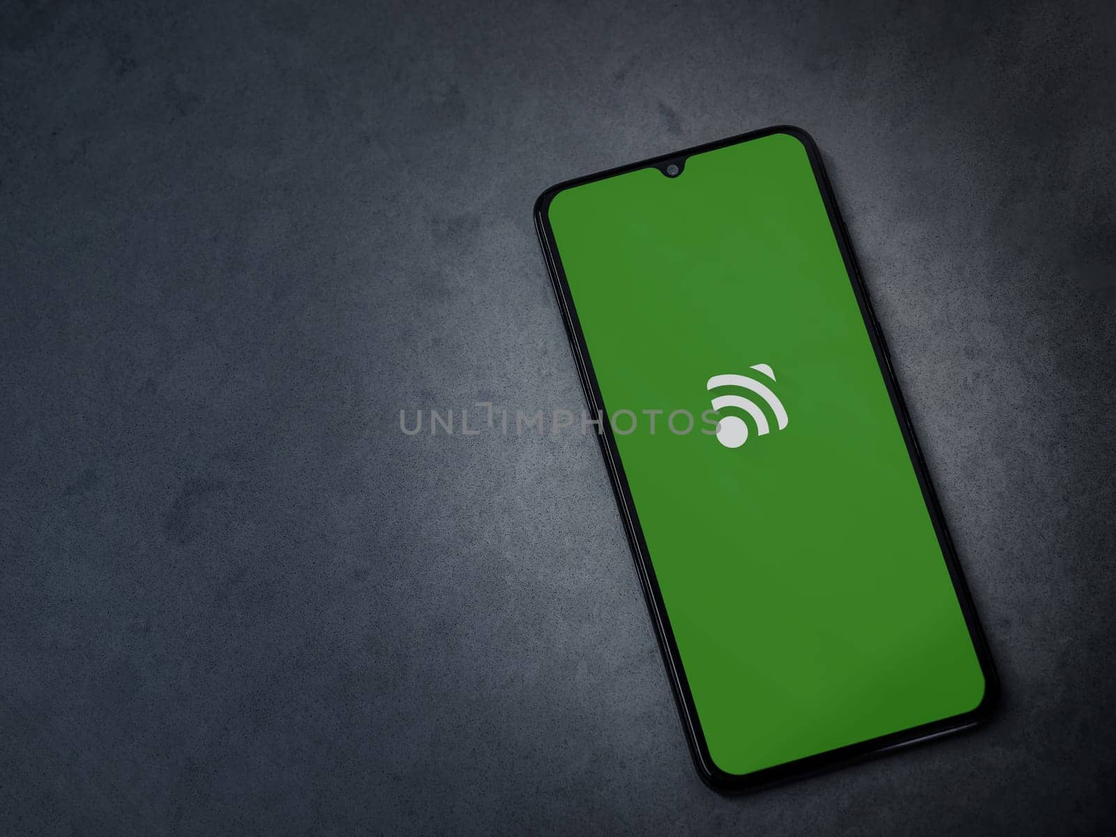 Lod, Israel - July 16,2023: Unified Remote app launch screen on smartphone on dark marble stone background. Top view flat lay with copy space.