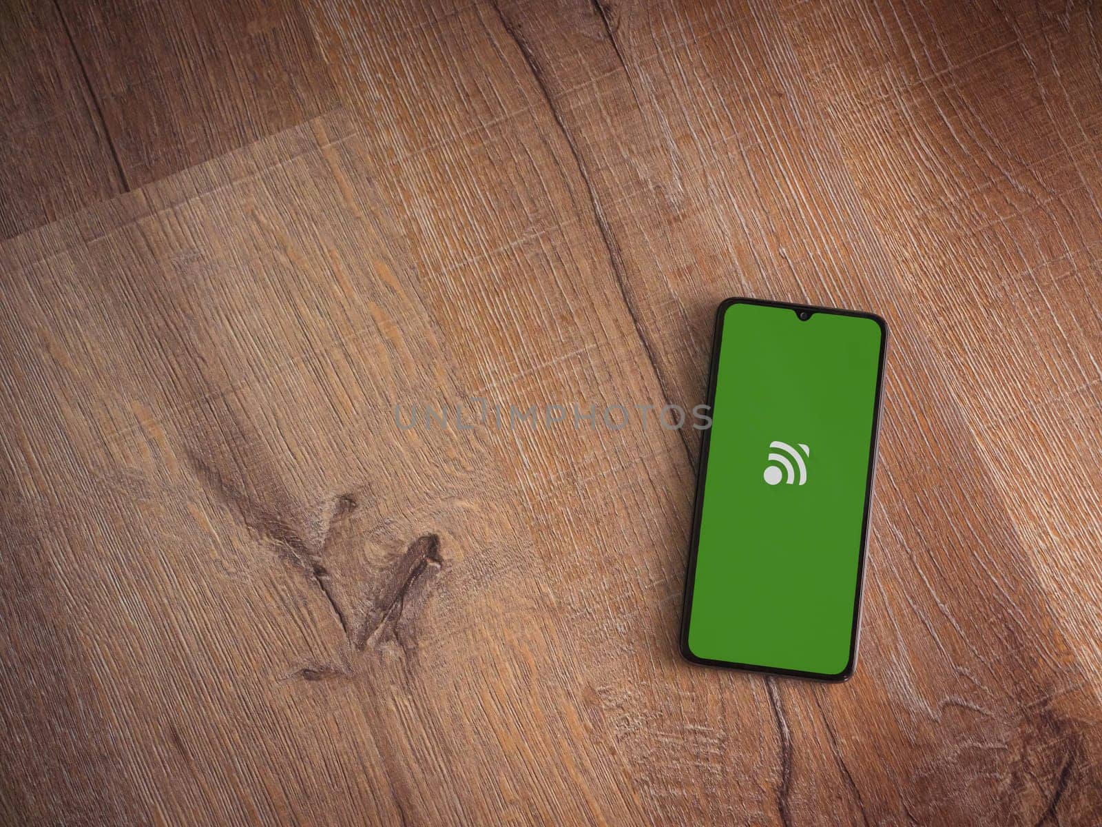 Lod, Israel - July 16,2023: Unified Remote app launch screen on smartphone on wooden background. Top view flat lay with copy space.