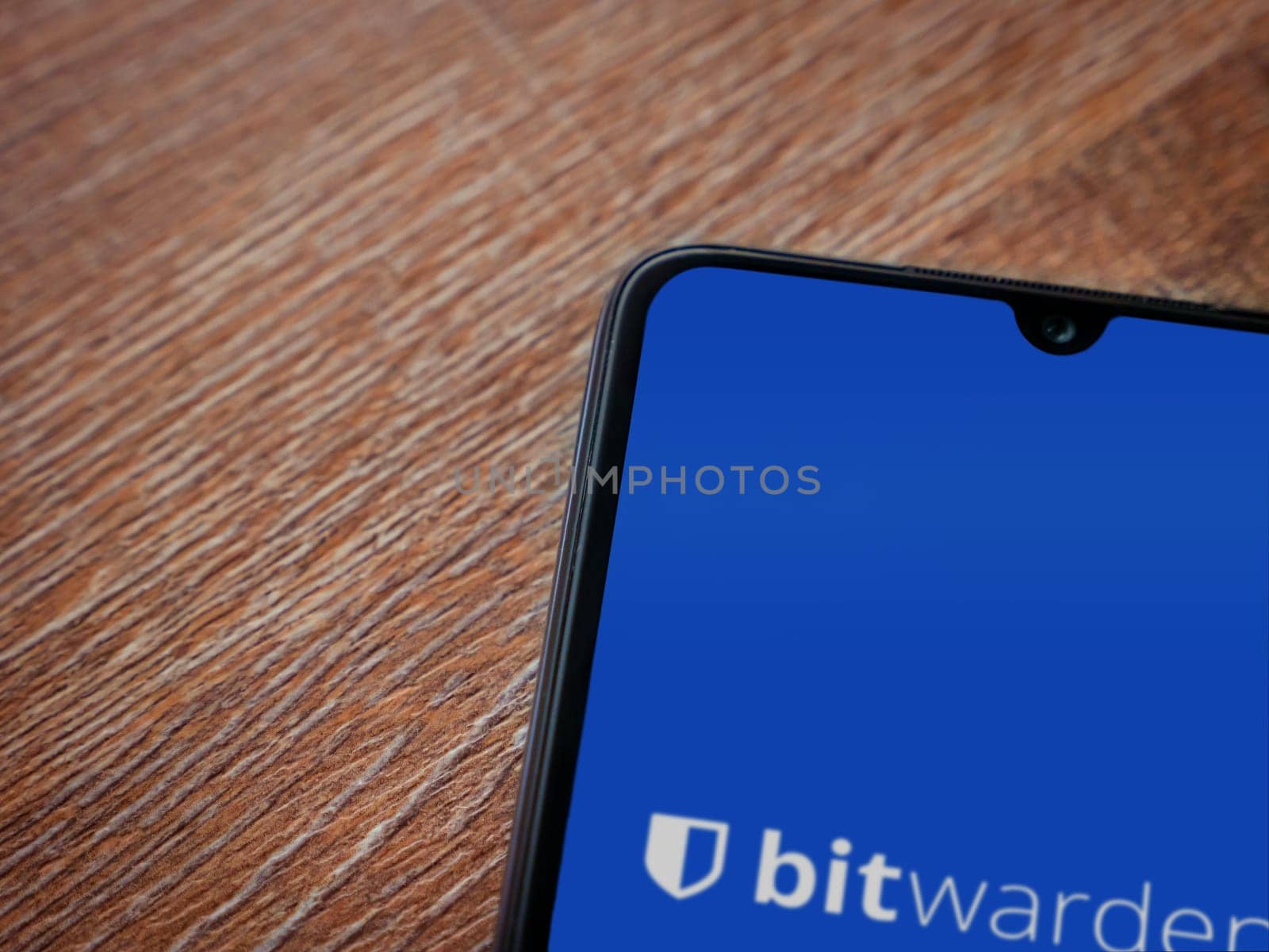 Lod, Israel - July 16,2023: Bitwarden Password Manager app launch screen on smartphone on wooden background. Top view flat lay with copy space.