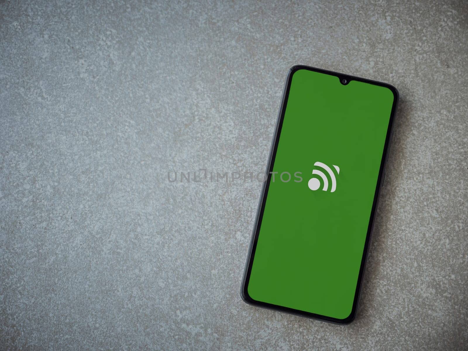Lod, Israel - July 16,2023: Unified Remote app launch screen on smartphone on ceramic stone background. Top view flat lay with copy space.