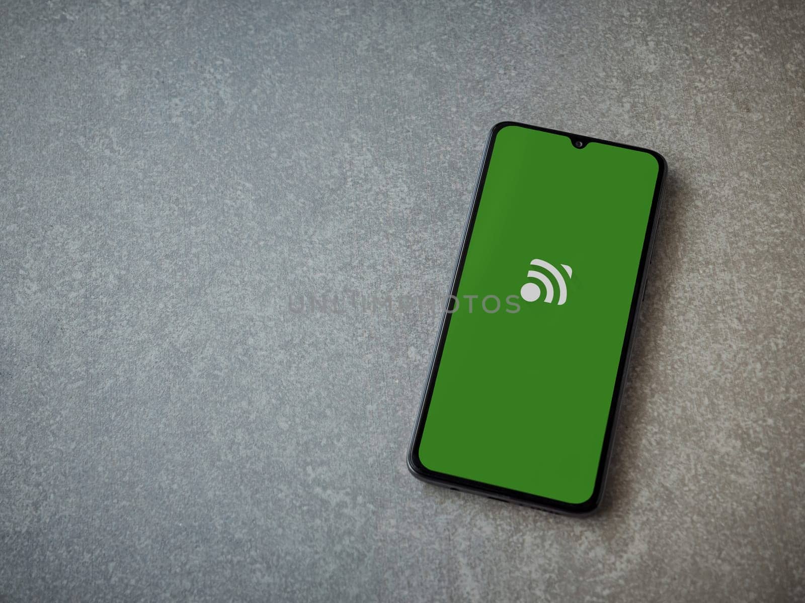 Lod, Israel - July 16,2023: Unified Remote app launch screen on smartphone on ceramic stone background. Top view flat lay with copy space.